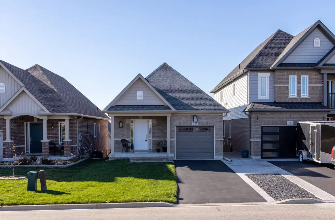Detached homes with garages, driveways and front lawns along a residential street.